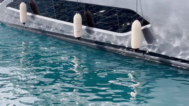 Sun glare on glossy board of mega yacht, anchor, tranquillity in port Hercules, bow of moored huge boat at sunny day, Monaco, Monte-Carlo