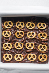 Top view of chocolate pretzel fudge in a baking tin, process of making chocolate pretzel fudge