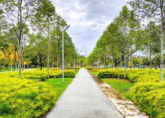 Titiwangsa City Park Breathtaking Picturesque View of Leading Lines Walkway on a Sunny Blue Sky Day, on the horizon there is two buildings, Warisan Merdeka Tower (KL118) and Kuala Lumpur Tower. 