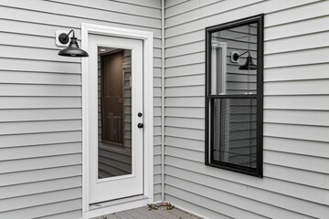Classic New Home Exterior with Grey Siding Featuring a Door with Glass Panel and A Side Window...
