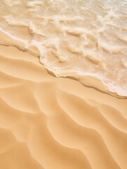 A close up of beach sand with a little blue water.  - obrazy, fototapety, plakaty
