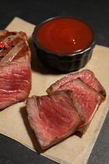 Delicious grilled beef steak with spices and tomato sauce on table