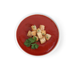 Delicious tomato cream soup with croutons and parsley in bowl isolated on white, top view