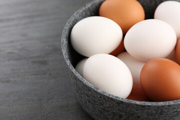 Unpeeled boiled eggs in saucepan on dark grey table, closeup. Space for text
