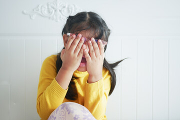 a upset child girl cover her face with hand 