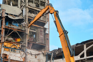 Fototapeta na wymiar Destroying of old industrial building by excavator destroyer