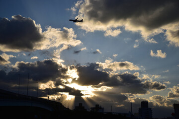 太陽の光差す雲の中を飛ぶ飛行機