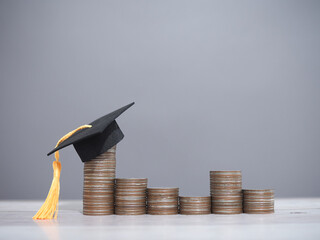 Graduation hat on stack of coins. The concept of saving money for education, student loan, scholarship, tuition fees