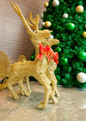 two gold color reindeers nearby a Christmas tree at vertical composition