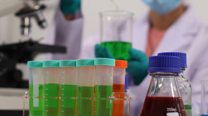 laboratory setting with colorful liquids in test tubes and a person wearing a lab coat and gloves.