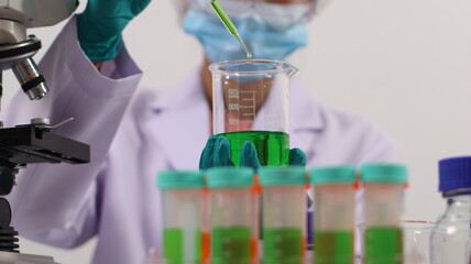 laboratory setting with colorful liquids in test tubes and a person wearing a lab coat and gloves.