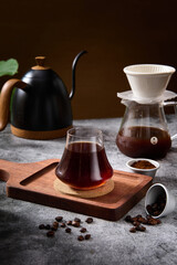 Hand brewed coffee and volcano shaped glass on wooden tray, professional shot indoors, studio light, dark background