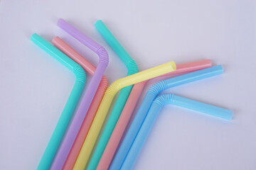 Colorful plastic drinking straws tubes for juice and cocktails, gray background. Concept, single use equipment for drinking, but can use for diy crafts for decoration.  