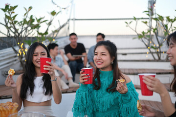 Cheerful young people having fun chatting together at a rooftop party.