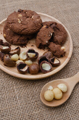 Soft Chewy delicious cookies with chocolate chips and macadamia on white wood plate
