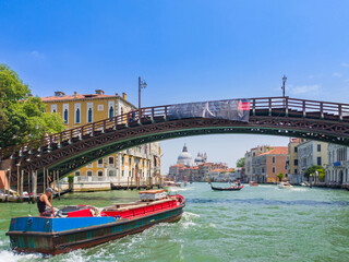 Fototapeta na wymiar Boat passing through under a big bridge in a canal (Venice, Italy)