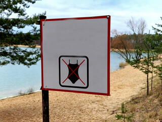 mark with a crossed out swimsuit symbol. nudist beach with sand and pine trees. it is not possible...