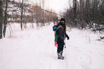 Fototapeta na wymiar A woman carrying a child in a winter forest hike