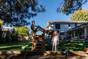 Toddler girl in diaper playing in backyard with brother