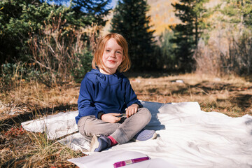 Smiling child sitting in the sun, looking at camera with happiness