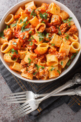 Italian pasta mezze maniche with bolognese sauce closeup on the plate on the table. Vertical top view from above