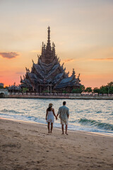 A diverse multiethnic couple of men and women visit The Sanctuary of Truth wooden temple in Pattaya...