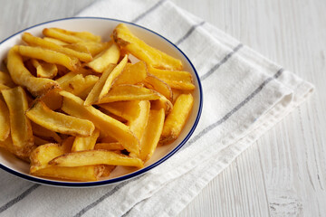 Homemade French Fries with Ketchup on a white wooden background, side view. Copy space.