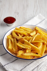 Homemade French Fries with Ketchup on a white wooden background, side view. Copy space.