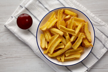 Homemade French Fries with Ketchup on a white wooden background, top view.