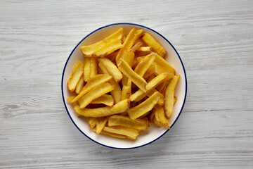 Homemade French Fries on a Plate on a white wooden background, top view.