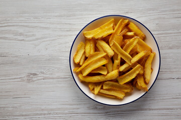 Homemade French Fries on a Plate on a white wooden background, top view. Copy space.