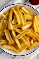 Homemade French Fries on a Plate on a white wooden background, top view. Close-up.