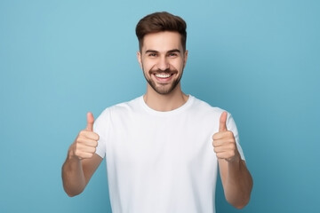 Portrait of cheerful man smiling and showing thumb up over blue background