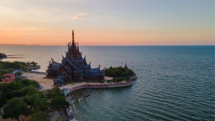 The Sanctuary of Truth wooden temple in Pattaya Thailand at sunset by the ocean, a gigantic wooden...