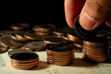 Close-up of female hand putting coin on a stack of coins