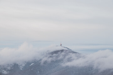 Highest peak of Beskydy mountains Lysa hora under the morning fog and white snow cover. Winter months on planet Earth