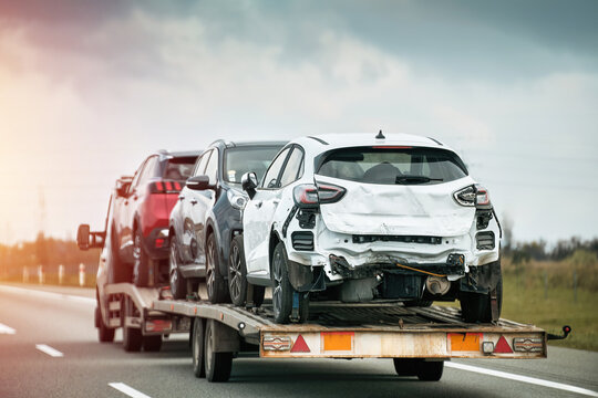 Tow truck carries three cars damaged beyond repair after a severe collision. The insurance company will pay the actual cash value. The cars might be restored or used for parts