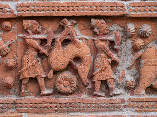 Closeup view of carved terracotta hunting scene of hunters carrying deer on ancient Govinda temple...
