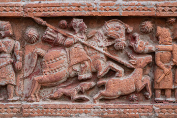 Closeup view of carved terracotta hunting scene of hunter on horse chasing deer on ancient Govinda...