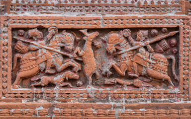 Closeup view of carved terracotta hunting scene of hunters riding horses chasing deer on ancient Govinda temple in Puthia religious complex, Rajshahi, Bangladesh
