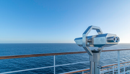 Jumelles sur le pont d'un navire de croisière en navigation en mer avec un ciel bleu.	