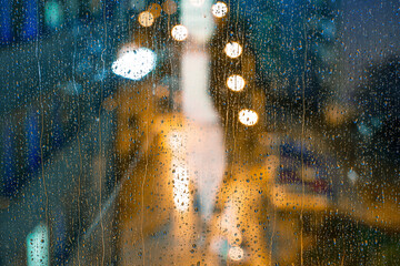 Water drops on the window pane, glass. Lights of the city. Bokeh - abstract vivid colorful background. 