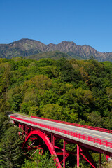 赤い橋で有名な清里の東沢大橋。背景に八ヶ岳と青空【縦カット】