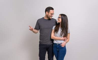 Romantic man with arm around girlfriend holding hands and looking at each other on white background