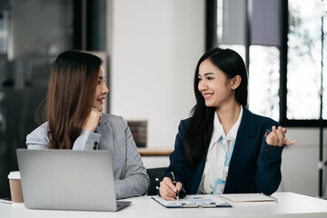 Business documents on office table with smart phone, tablet and laptop computer and graph with social network diagram and two colleagues discussing data in office.