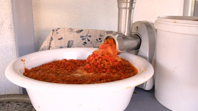 Grind red peppers in an electric meat grinder. Selective focus.