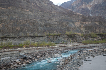 A river stream flows through a mountain landscape. Image of Shyok river in Turtuk, Ladakh