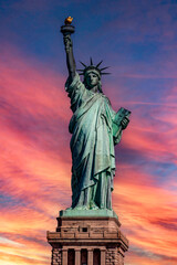 Vertical photograph of the Statue of Liberty in the Big Apple, under a reddish sky at sunrise, monument known as the lady of New York around the world