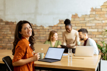 Business woman working on laptop with her young multiethnic startup team working in the modern office