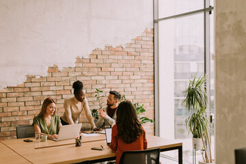 Young multiethnic startup team working by the brick wall in the industrial style office